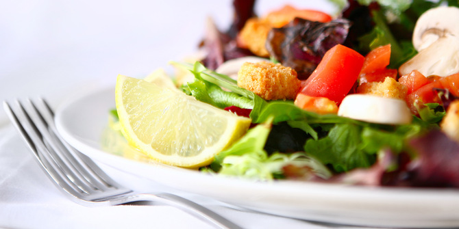 en sallad på en tallrik med en gaffel vid sidan av