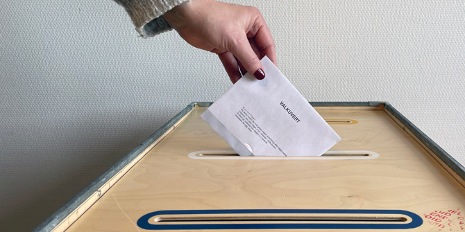 Hand som lägger ner valkuvert i låda med 3 fack