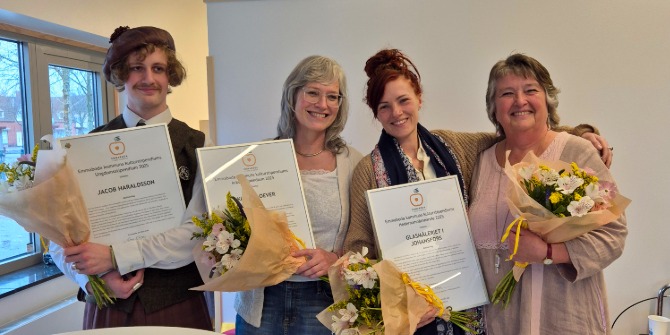 Fyra personer med blommor och diplom i händerna.