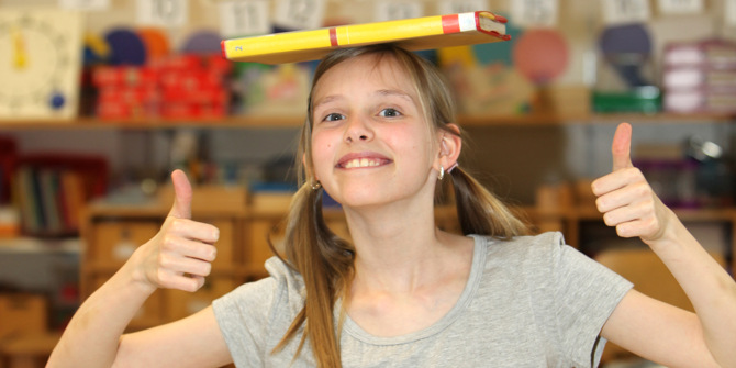 En ung flicka håller en penna ovanför sitt huvud.