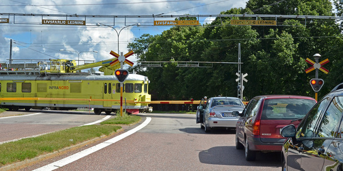 Bilar som står i kö vid järnvägsspår samtidigt som tåget kör förbi